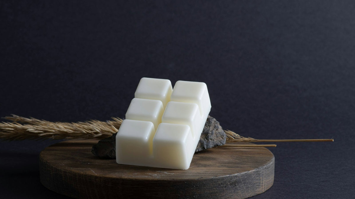 A white bar of wax melts on a round wooden board