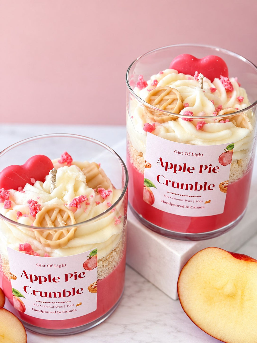 Two Apple Pie Crumble candles on marble showing the red wax base and golden crumble layer