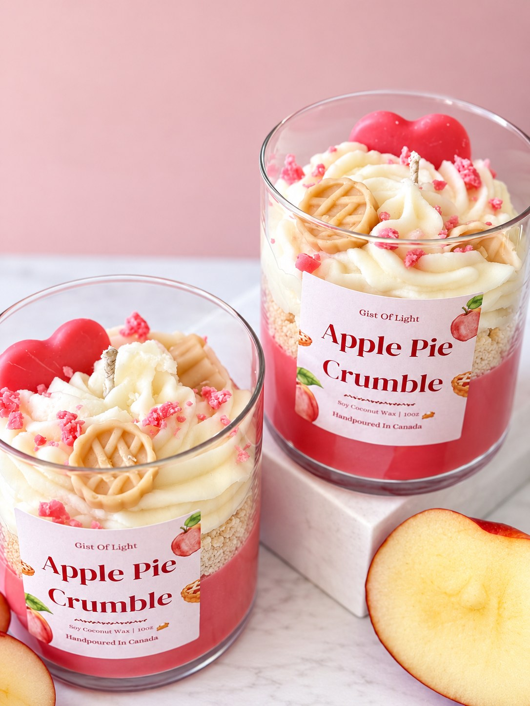 Two Apple Pie Crumble candles on marble showing the red wax base and golden crumble layer