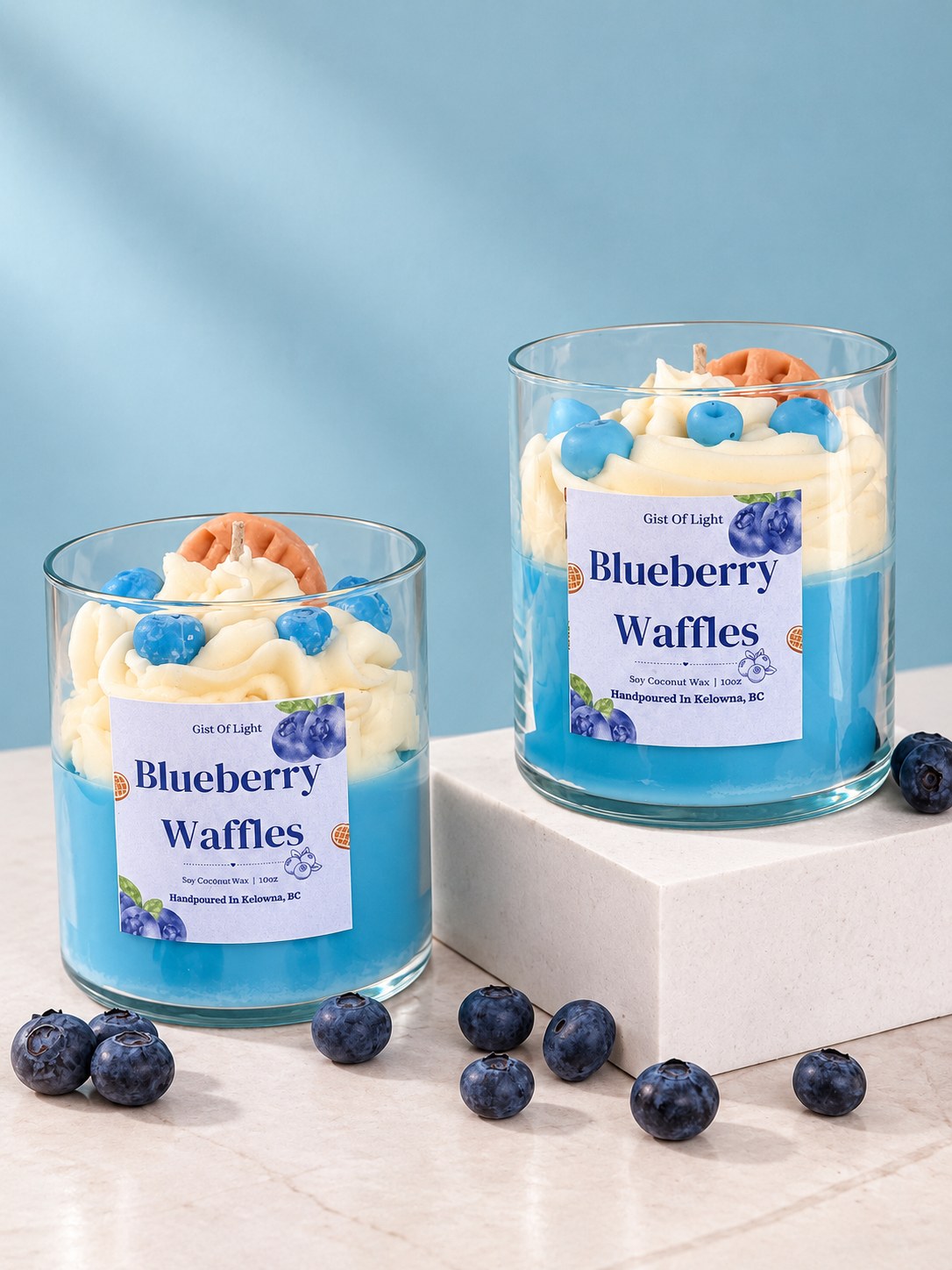 Two Blueberry Waffles bakery scented candles on a blue backdrop with fresh blueberries