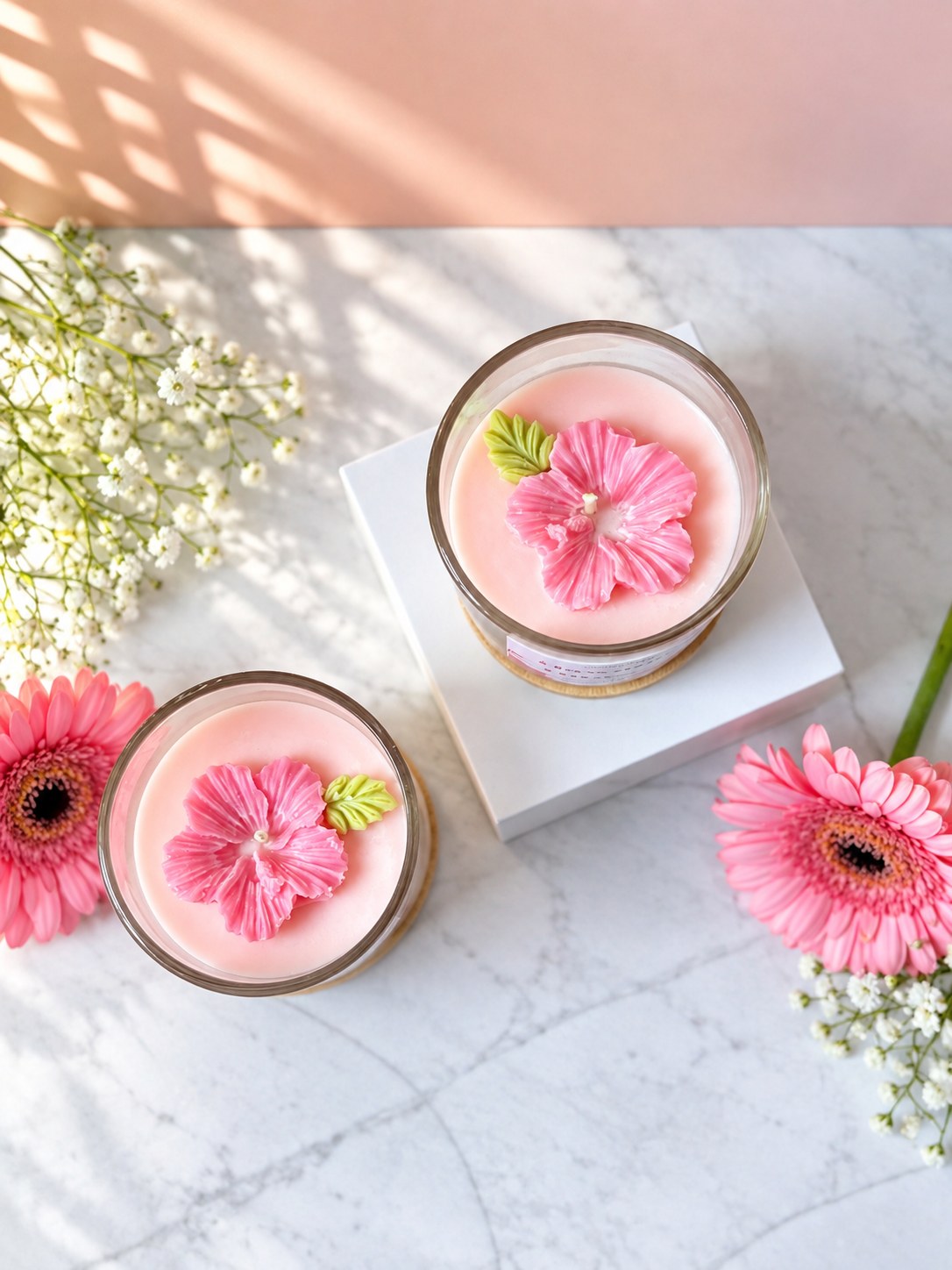 Two Hawaiian Hibiscus candles from above showing the moulded pink wax hibiscus and green leaf