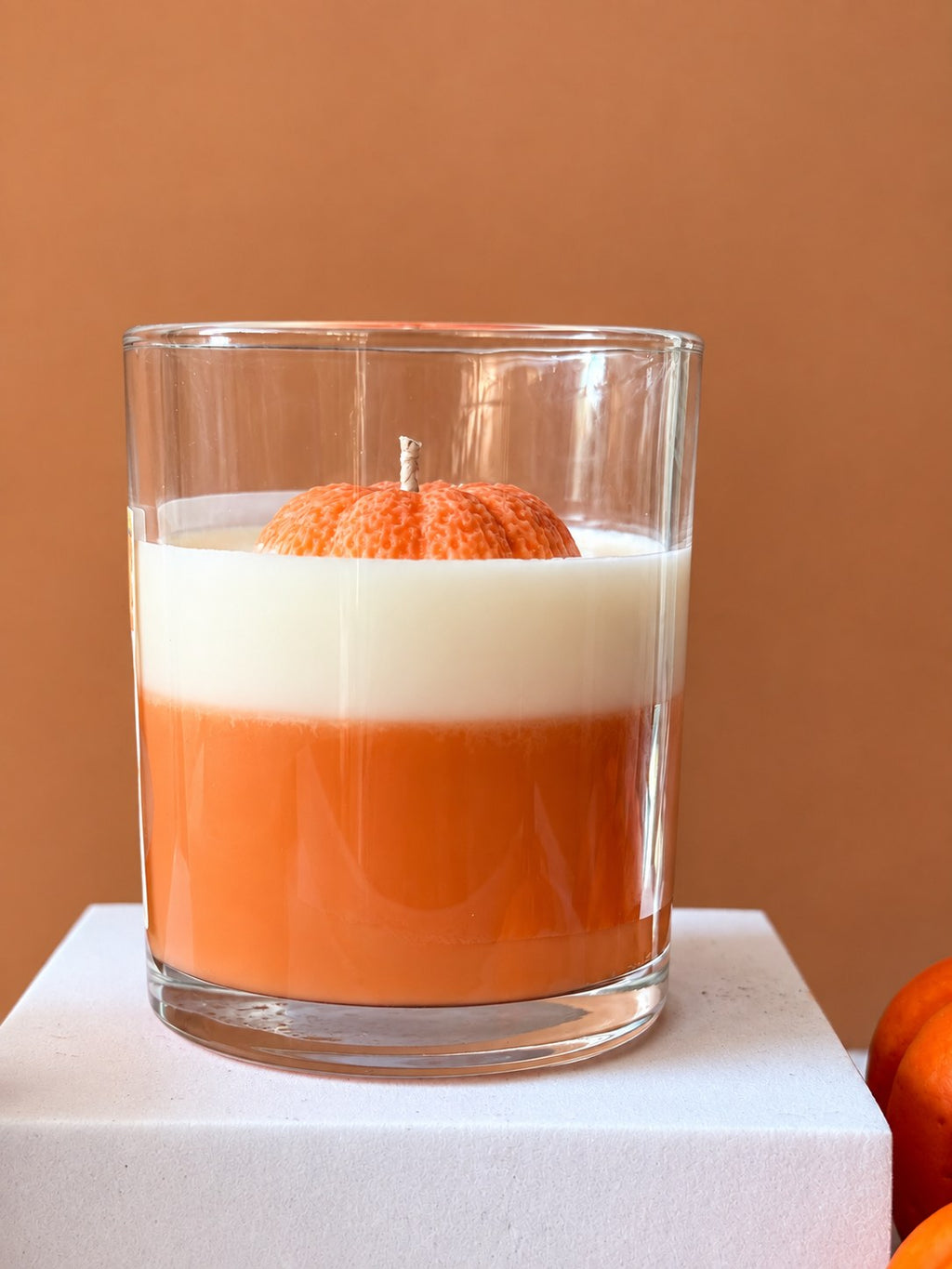 Side view of the Pumpkin Glow candle showing the orange wax base and white top layer