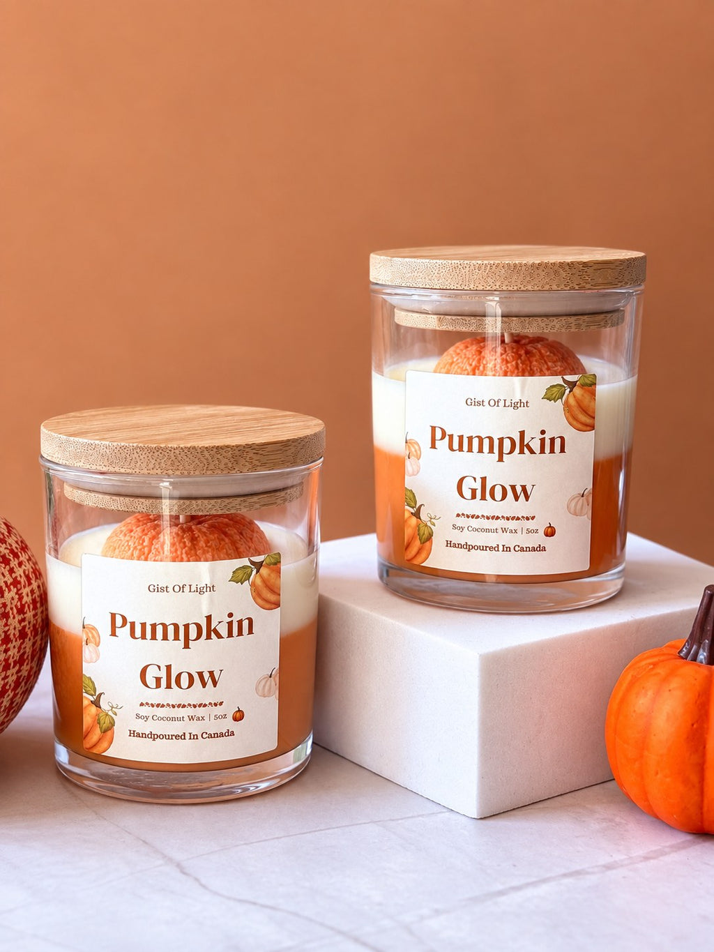 Two Pumpkin Glow spiced pumpkin pie candles on a marble surface with a woven pumpkin