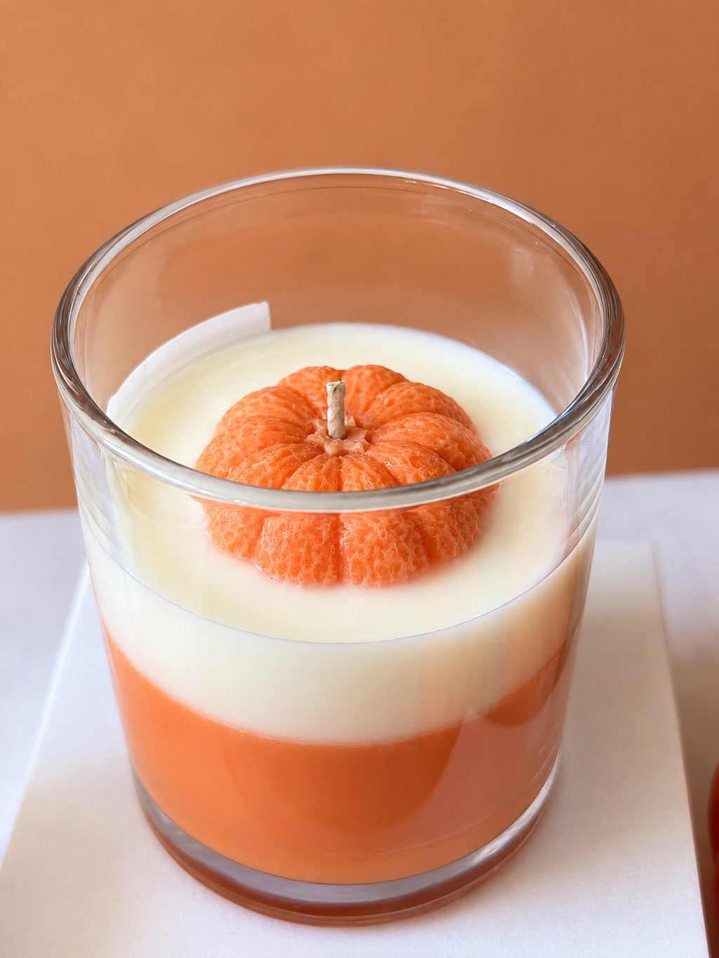 Close up of the Pumpkin Glow candle top with a moulded orange wax pumpkin around the cotton wick