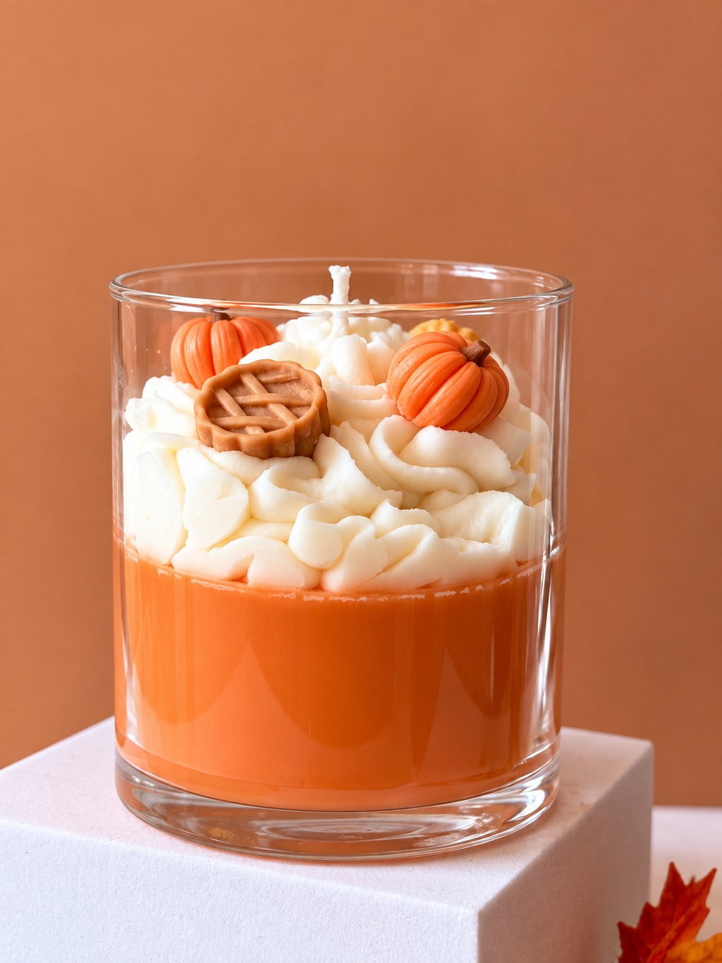 Pumpkin Pie Delight candle on a white plinth showing the orange wax base and white whipped top