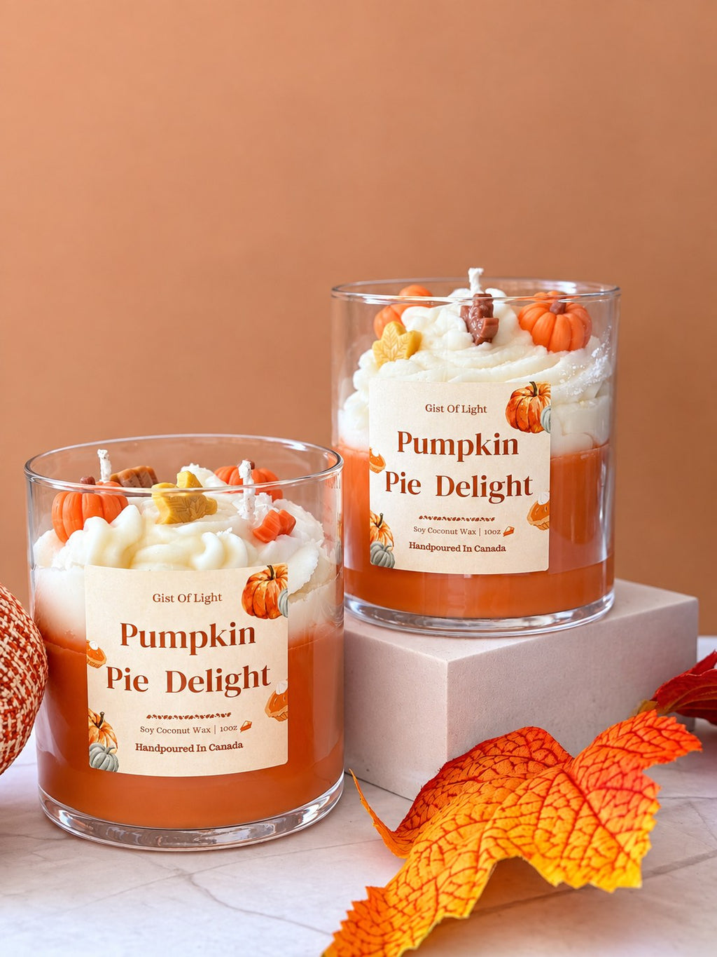 Two Pumpkin Pie Delight fall candles with orange autumn leaves