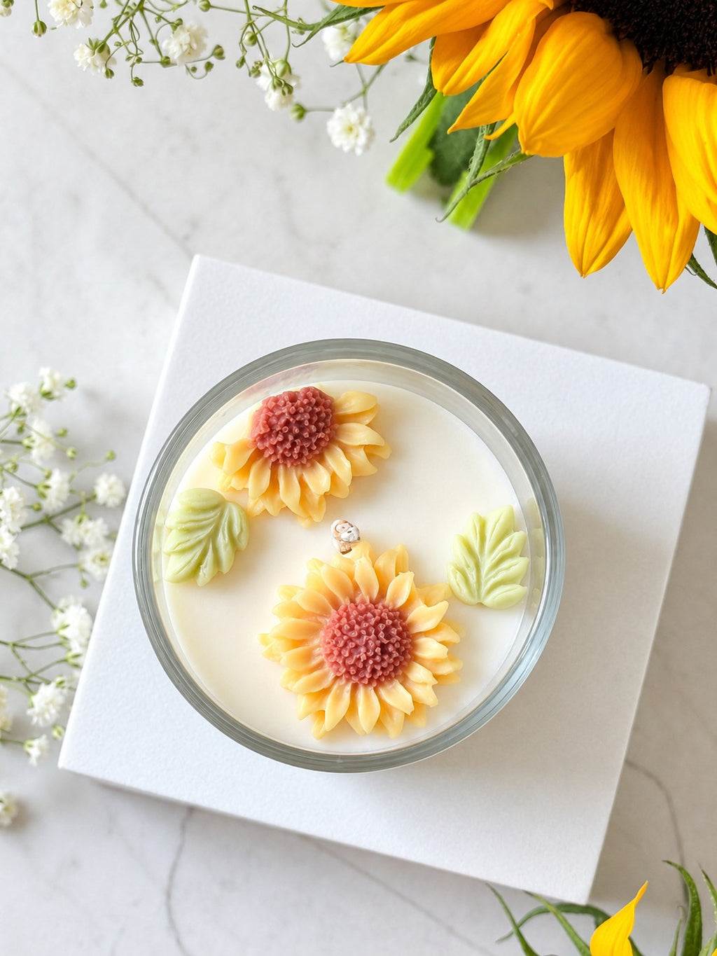 Sunny Hope candle from above showing two moulded wax sunflowers and green wax leaves
