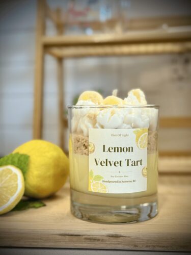 Lemon Velvet Tart candle with lemon slices on a wooden surface.