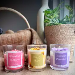 Colorful scented candles in glass jars with floral and herbal labels.