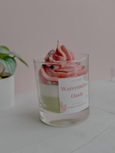 Fresh watermelon-themed candle in a clear glass with pink wax and a label.
